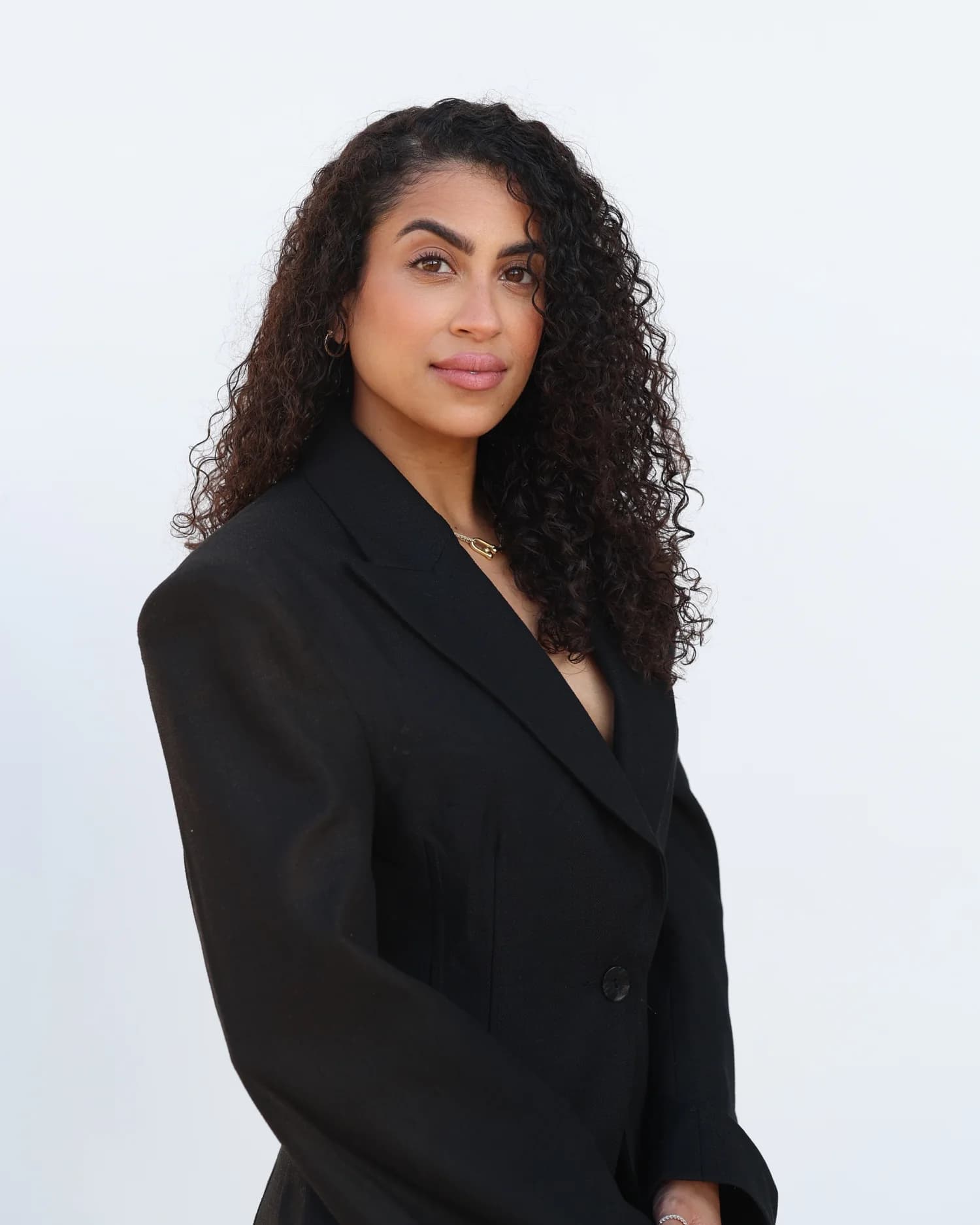 Rossy M. Peralta in a black tailored blazer against a clean white studio backdrop
